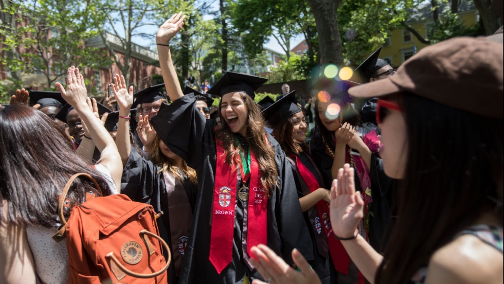 Fabiola Porras in cap and gown high-fiving fellow graduates