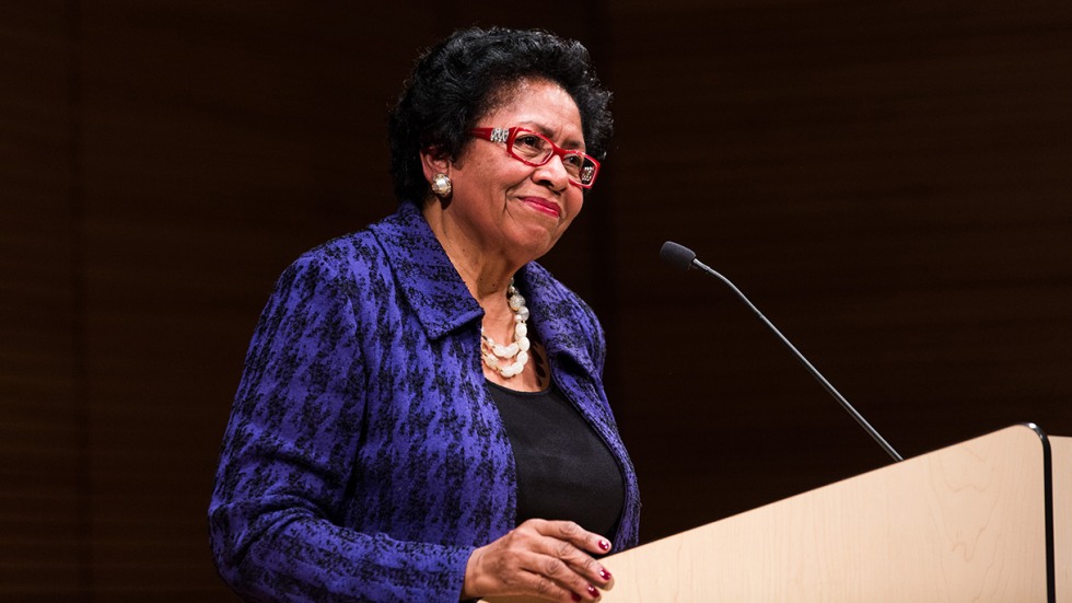 Ruth Simmons smiling at podium wearing purple