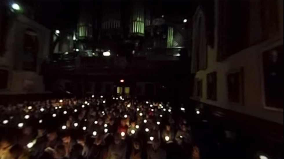Video screenshot of audience holding lit candles
