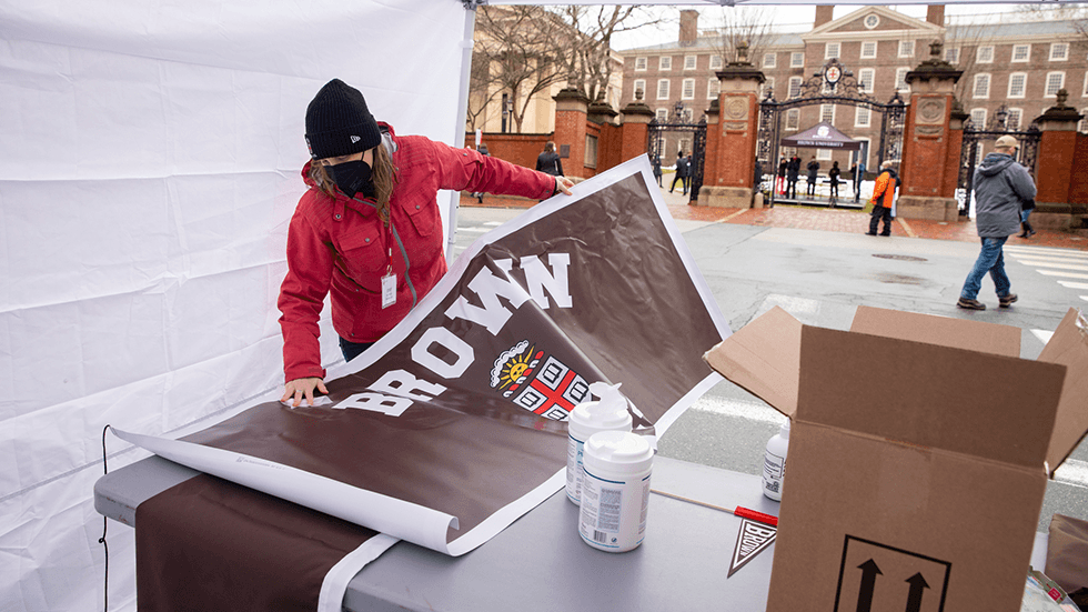 A Brown staff member handles a vinyl sign.