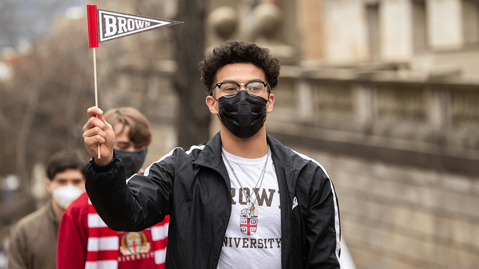A masked student waves a Brown pennant.