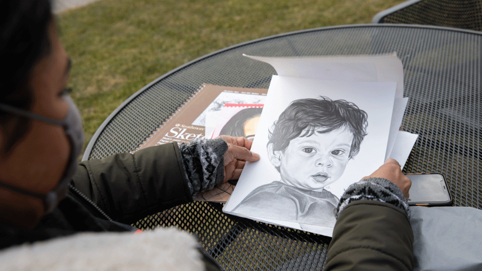 woman holding pencil sketch of a young boy