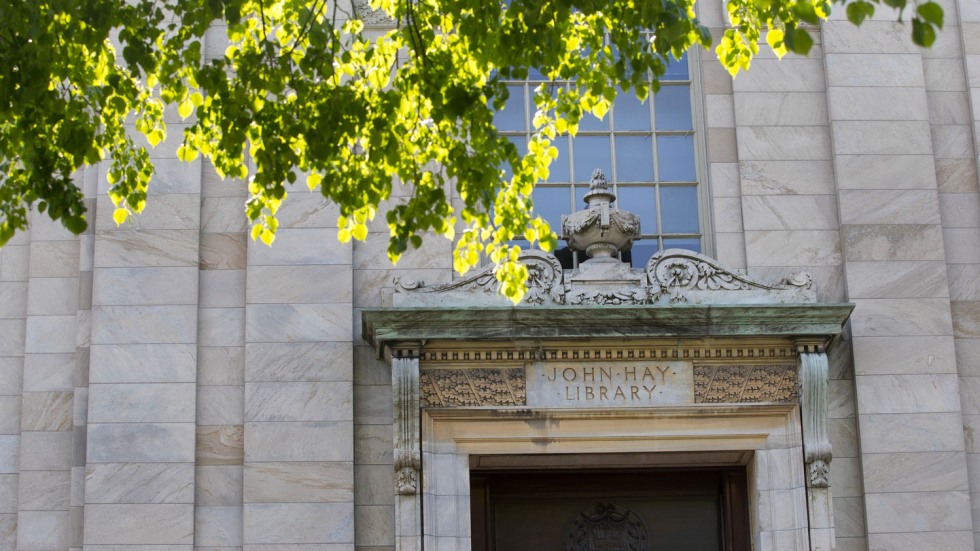 marble facade of the John Hay Library fronted by a sun-dappled tree