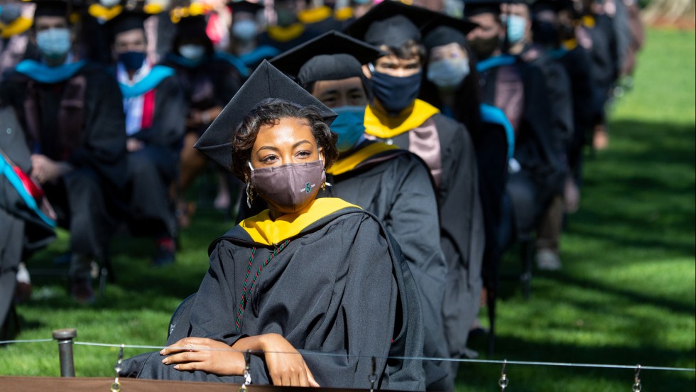 hooded graduates sitting in a row