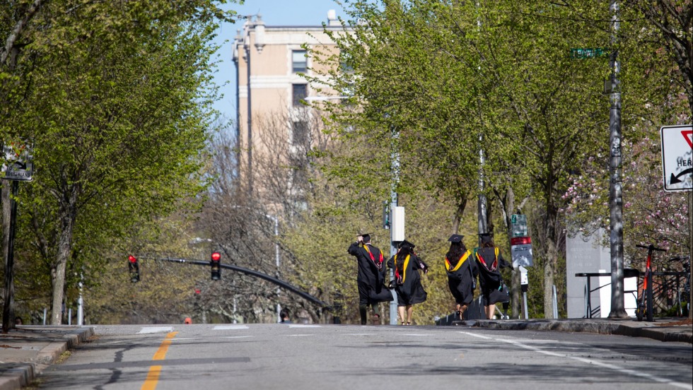 students running down a street in graduation gowns