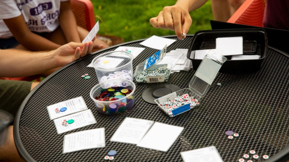 three people holding cards and picking up tokens
