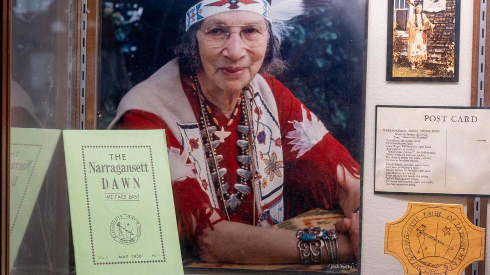 museum display case featuring a copy of the Narragansett Dawn and a portrait of Princess Red Wing