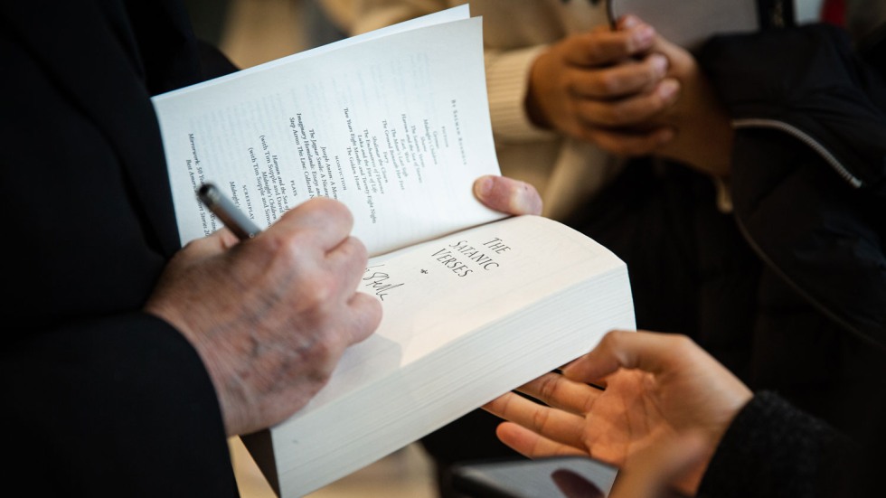 Salman Rushdie signing a copy of "The Satanic Verses"