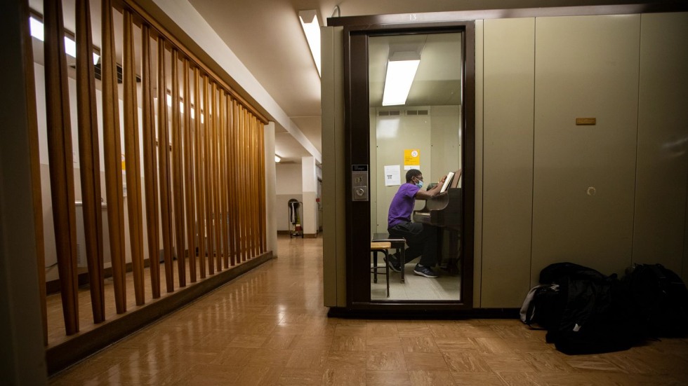 Derrick Pennix Jr. sitting at a piano inside a small room