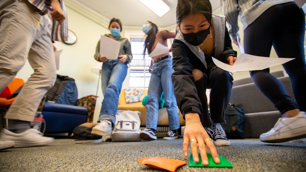 student reaching for a green bean bag