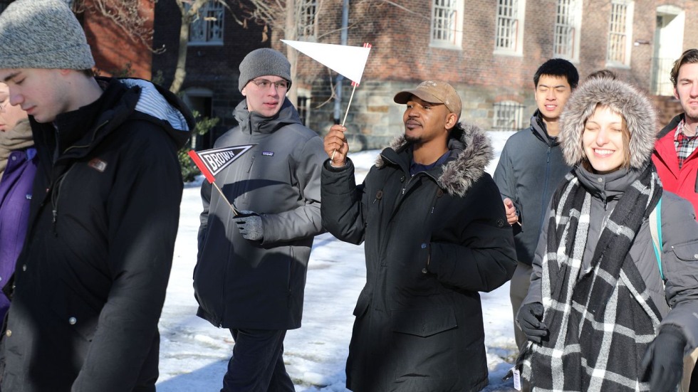 Anthony Moore waving a Brown pennant among a procession of other students