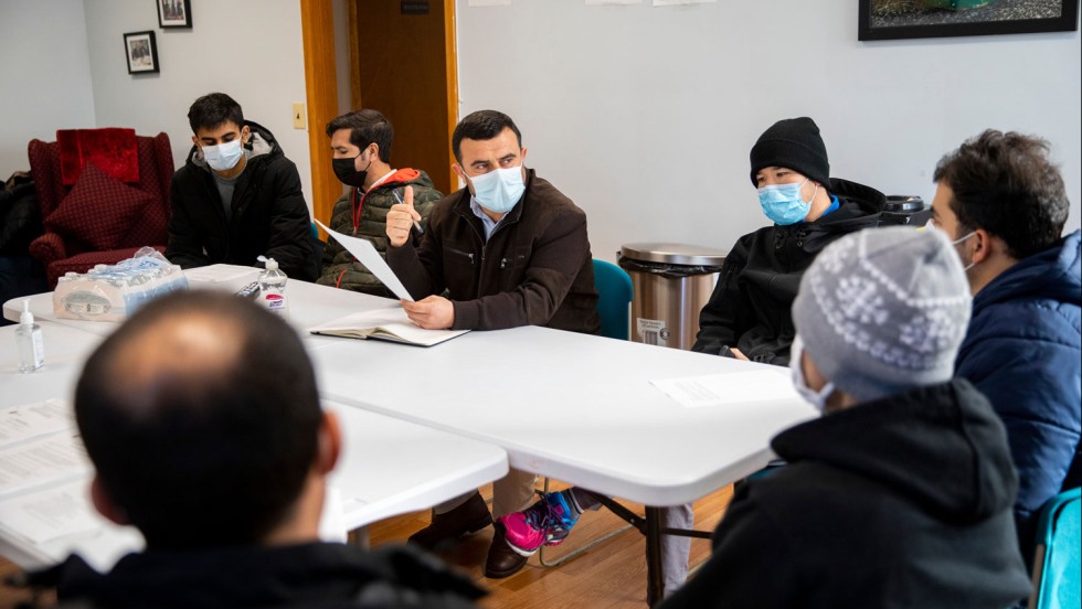 Masked men sitting around a folding table