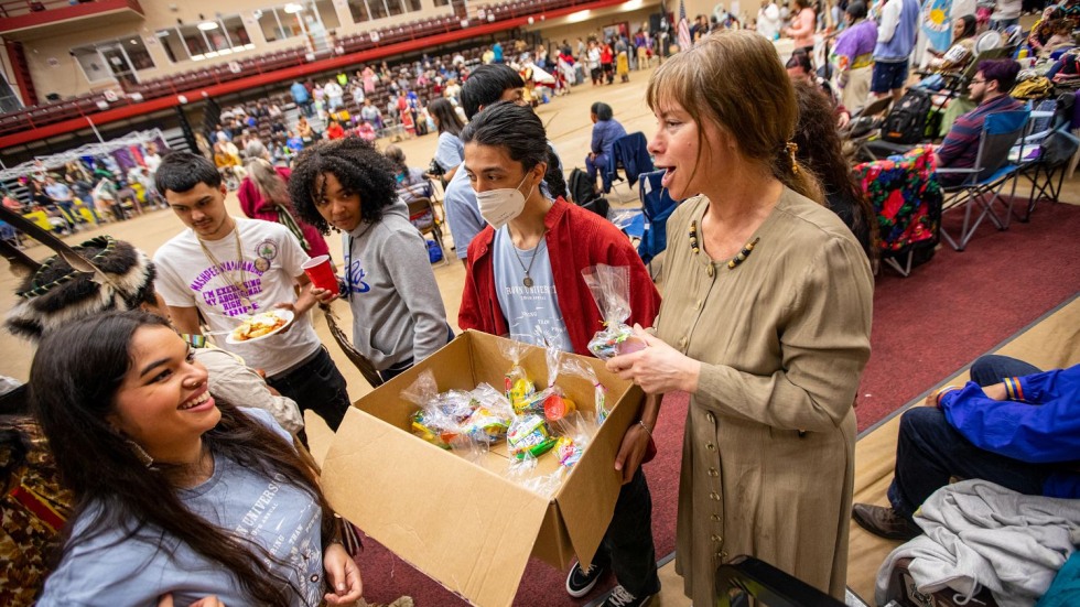 people gathered in a circle with a box of treats