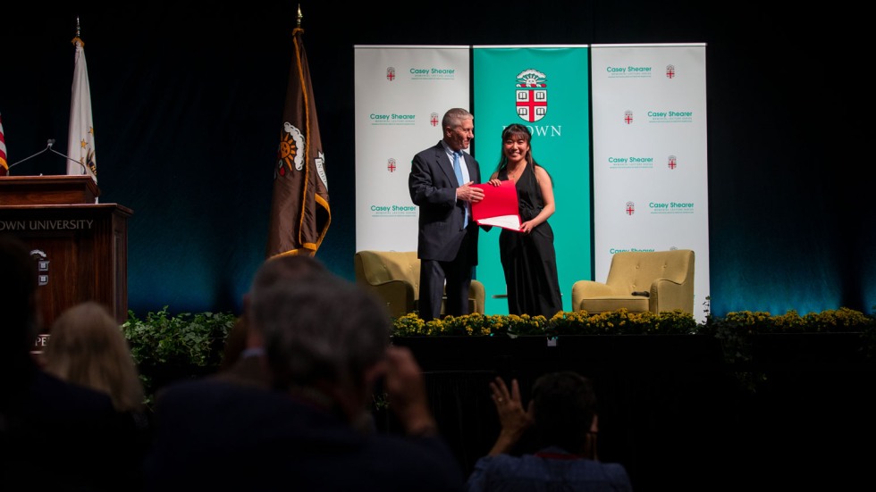 man handing a paper award to a woman