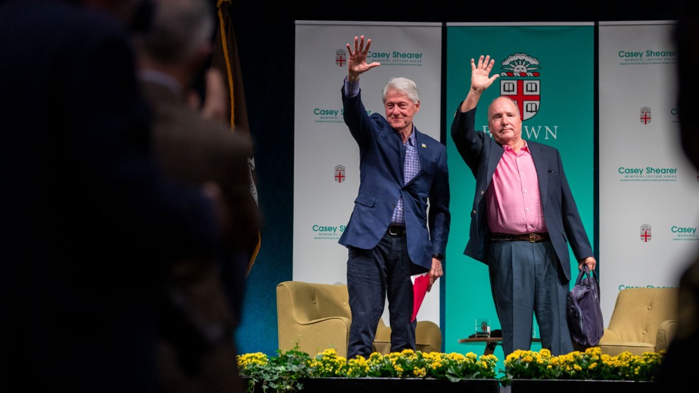 Bill Clinton and Derek Shearer waving to an audience
