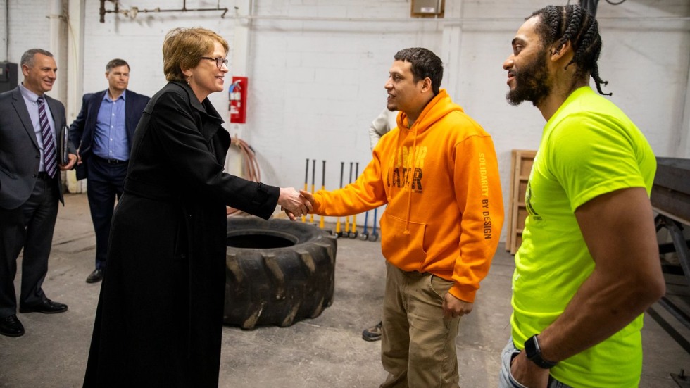 Two people shaking hands with others looking on