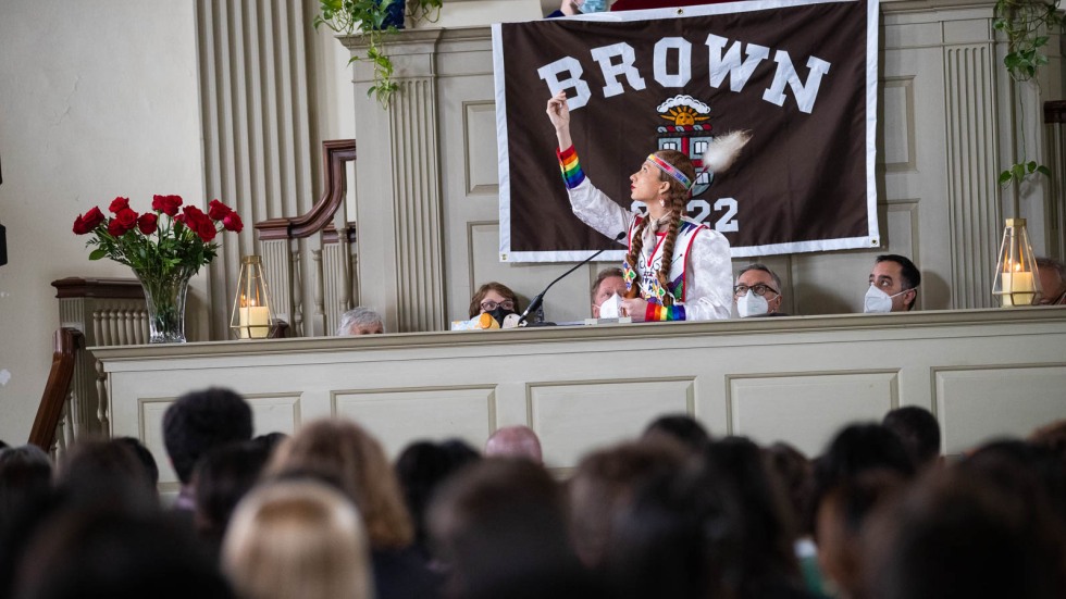 person dressed in traditional Narragansett regalia speaking at a podium