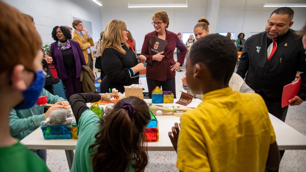 group of adults and children gathered around an engineering experiment on a table