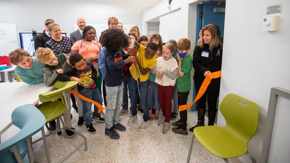 elementary school students cutting a ribbon with large scissors