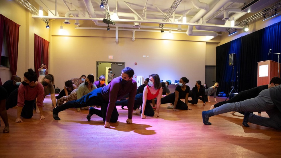 people stretching their legs on the floor of a rehearsal room