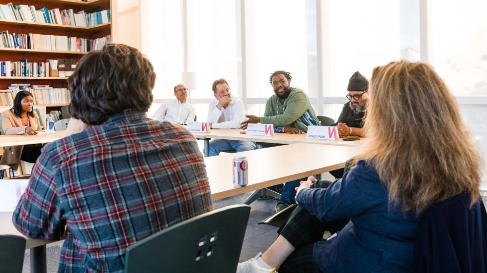 Questlove sitting around a seminar table talking to faculty and students