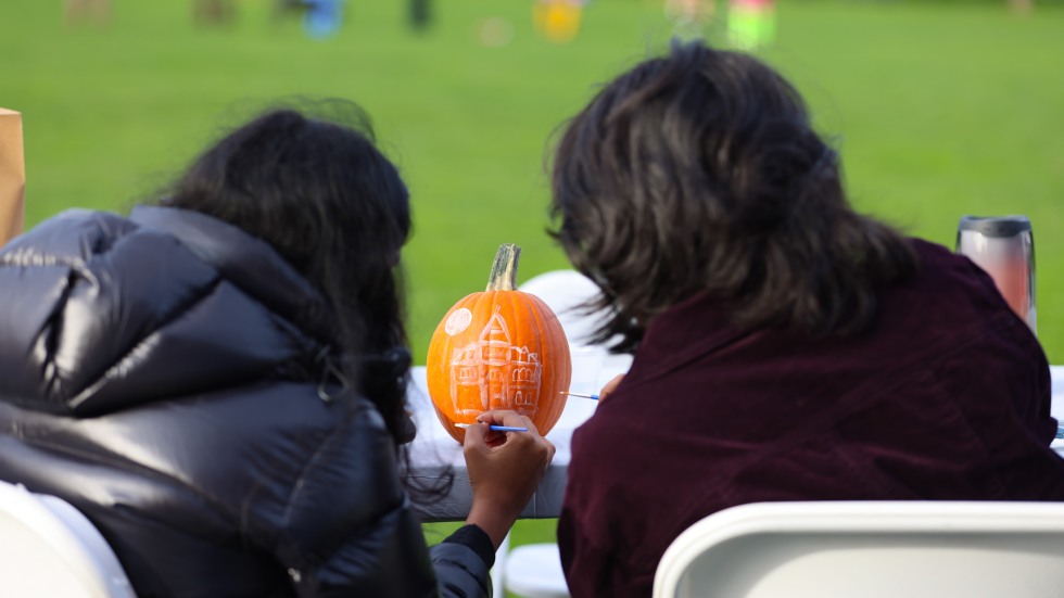 two students paint a pumpkin