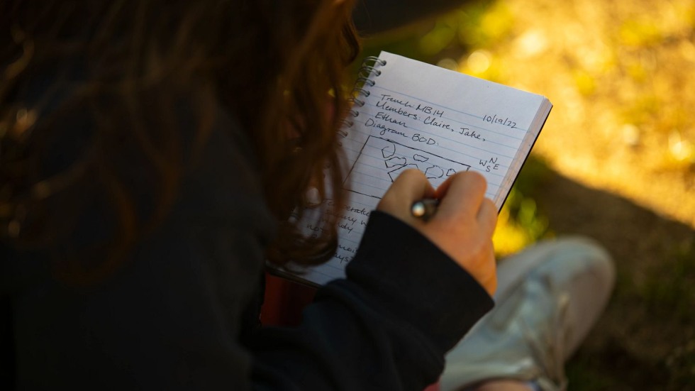 student writing and drawing in a notebook