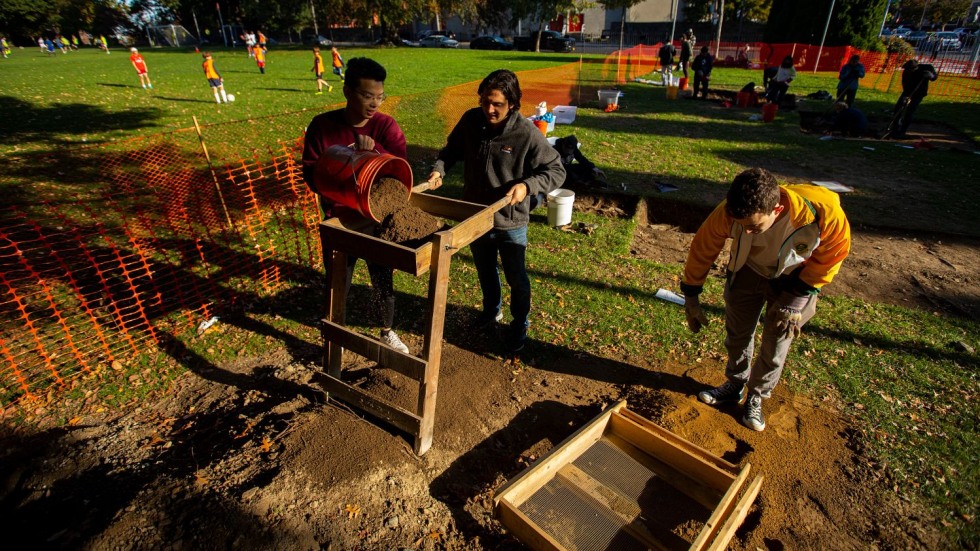 students sifting dirt at an archaeological site