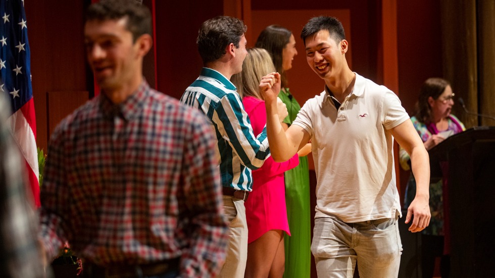 two students high fiving each other on a stage