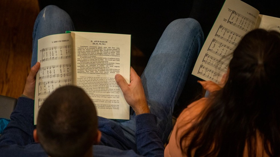people reading a program with sheet music and Latin text