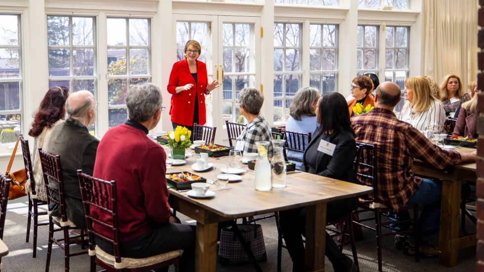 President Paxson speaks to a table of employees eating lunch