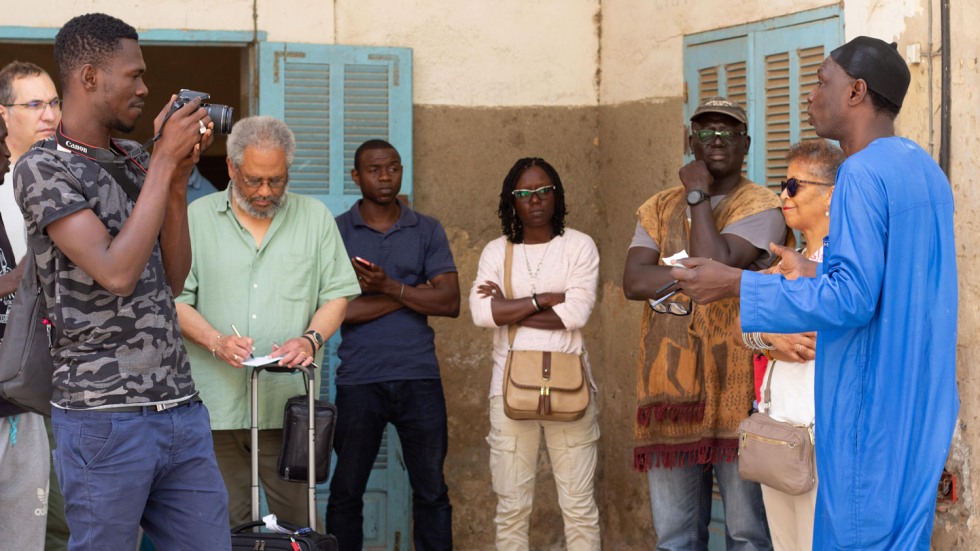 group of people photographing and interviewing a Senegalese man