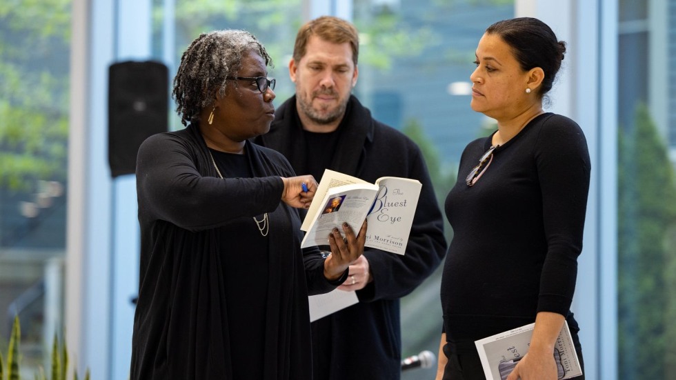 Noliwe Rooks, Matthew Guterl and Juliet Hooker talking while looking at a copy of "The Bluest Eye"