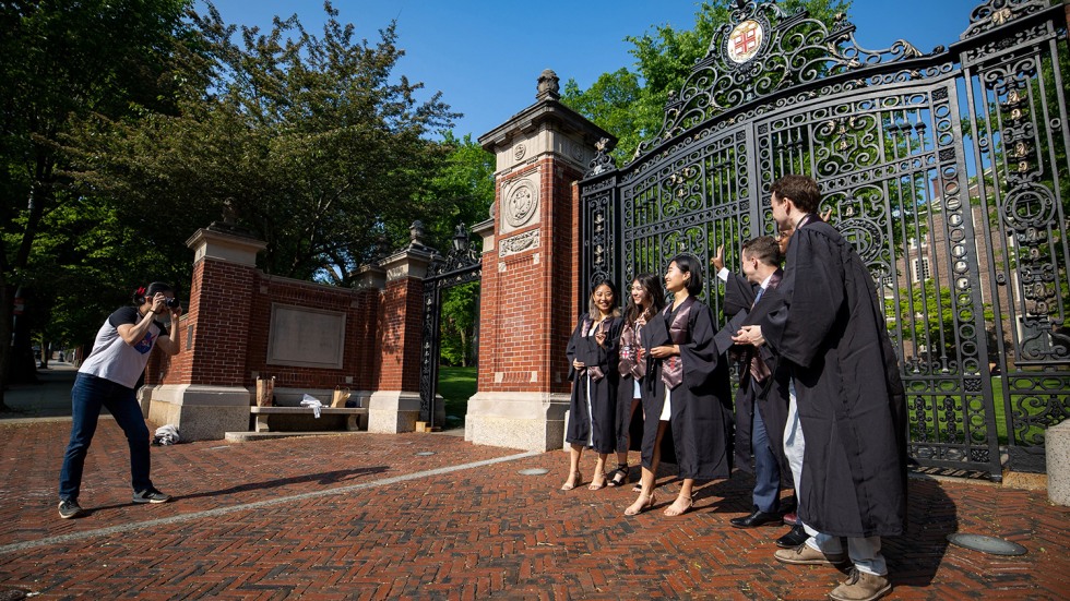 Graduates in regalia pose for a photo at the Van Wickle Gates