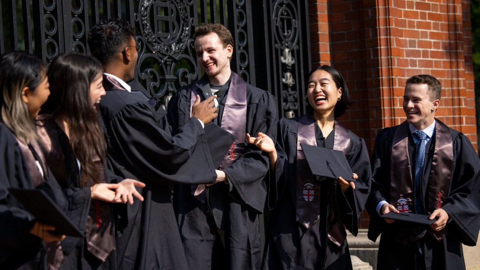 Seniors gather in their graduation regalia by the Van Wickle Gates