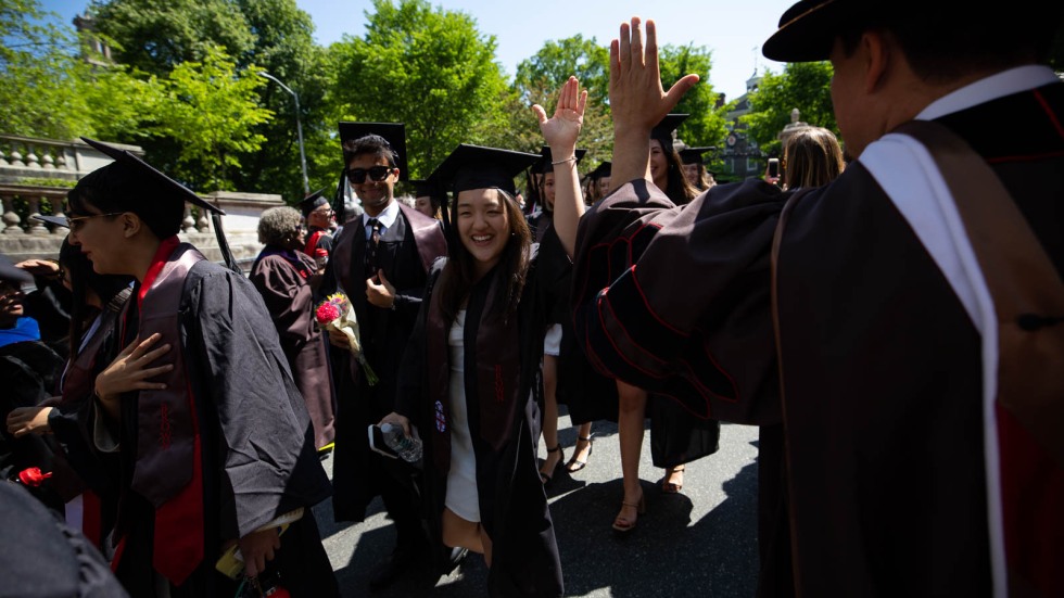 student high fiving a faculty member in regalia