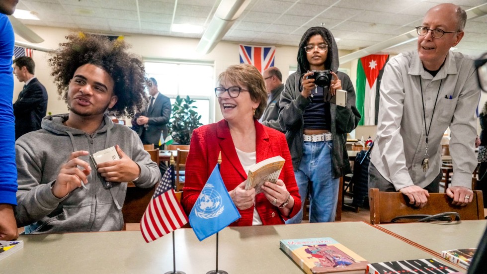 Christina Paxson holding a book and laughing with a high school student