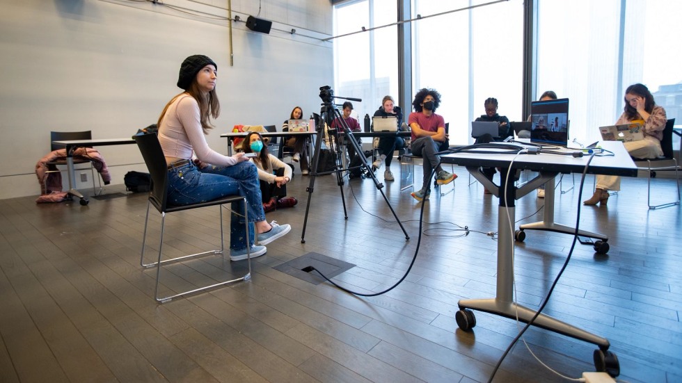 Stephanie Stiles sitting in front of other students in a light-filled studio