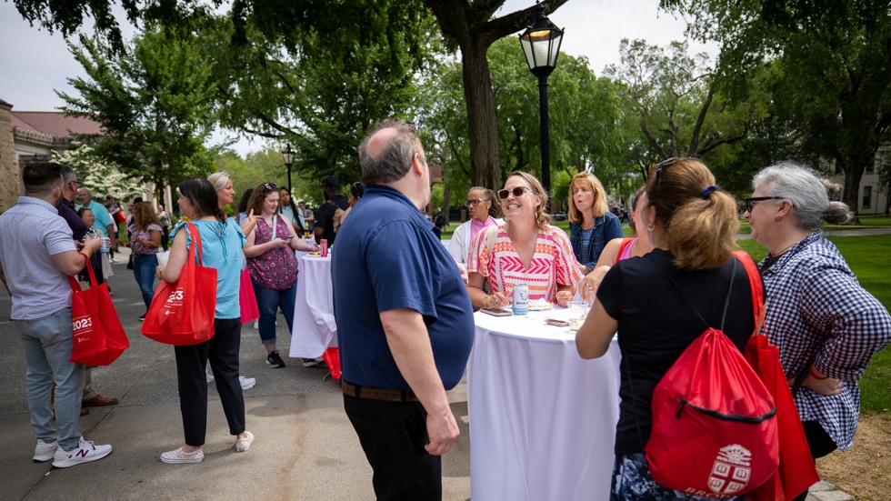 Staff stand at an outdoor table and talk to each other