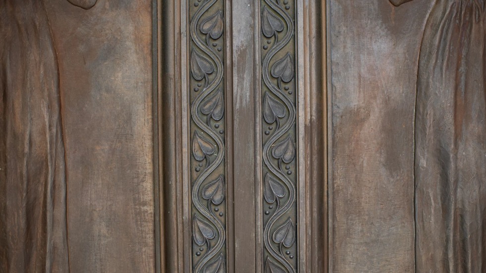 Detailed etchings of leaves within the bronze doors 