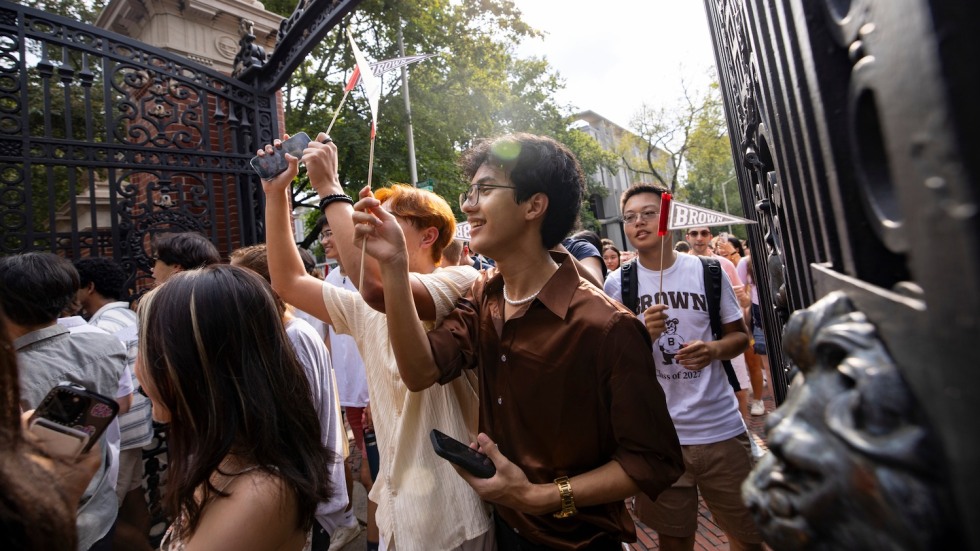 students walking through the Van Wickle Gates, waving pennants