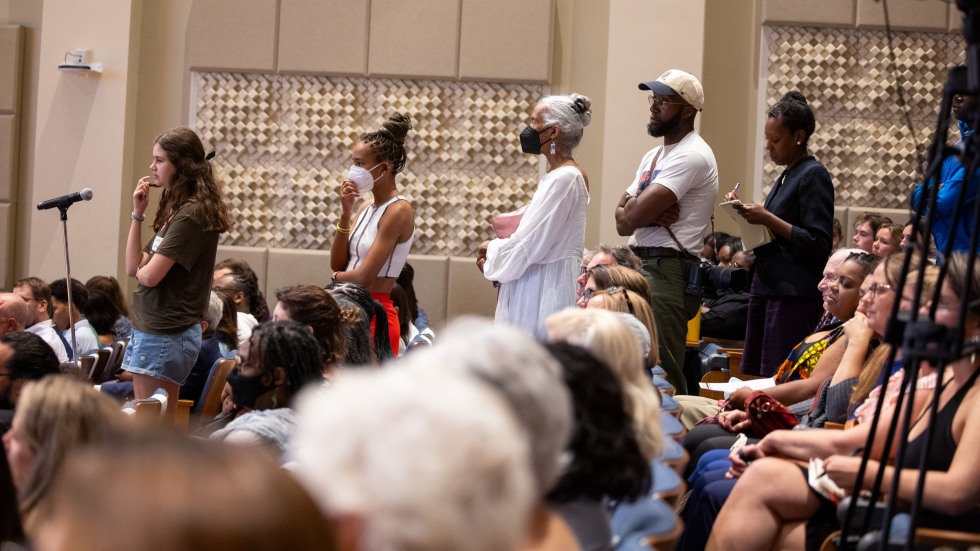 five people standing in line in front of a microphone