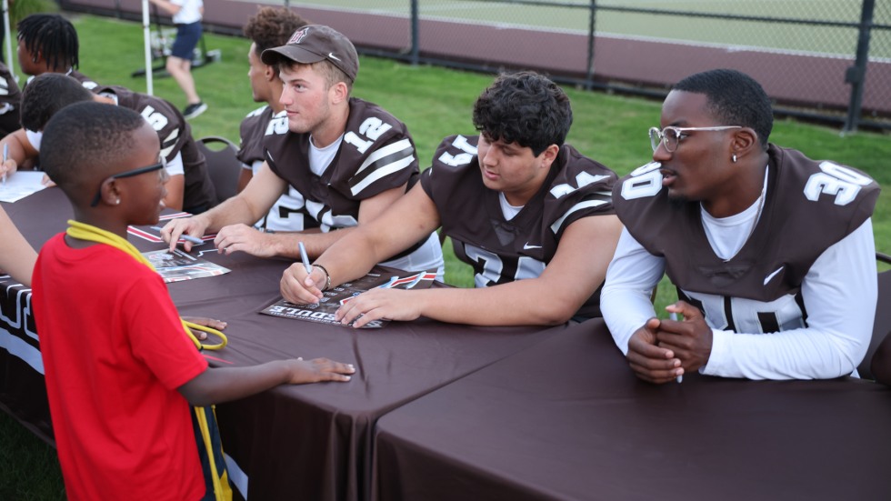 Brown football players sign a poster 