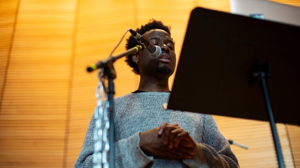 man singing at a microphone with a chain hanging from the stand