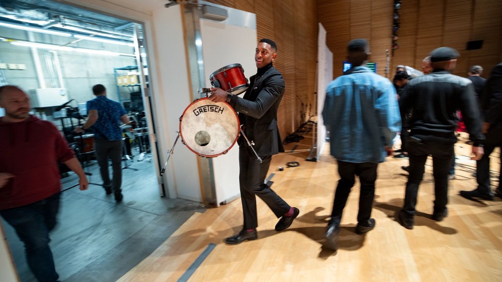 man walking through a hallway with a drum kit