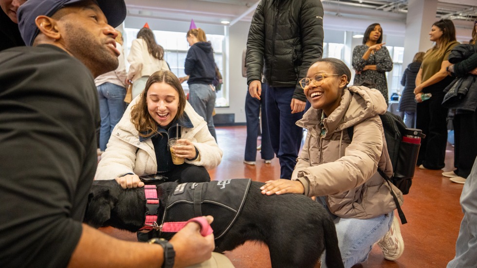 Two students pet Elvy the dog