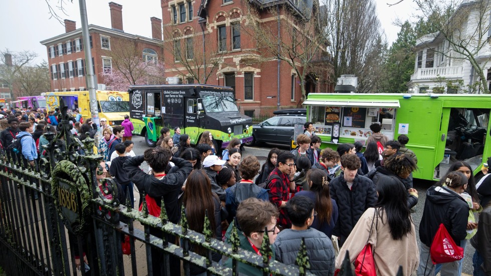 People gather at a row of food trucks