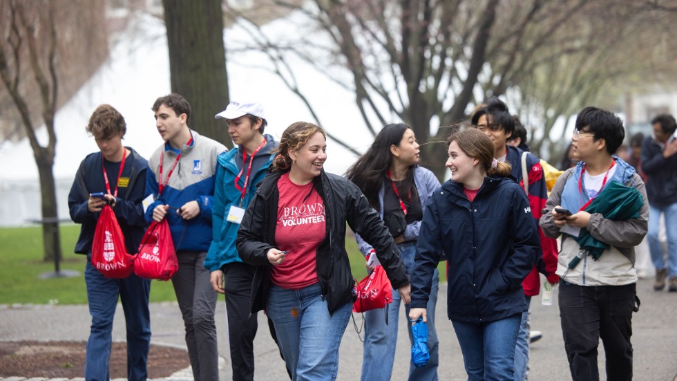 A group of people walks on the College Green