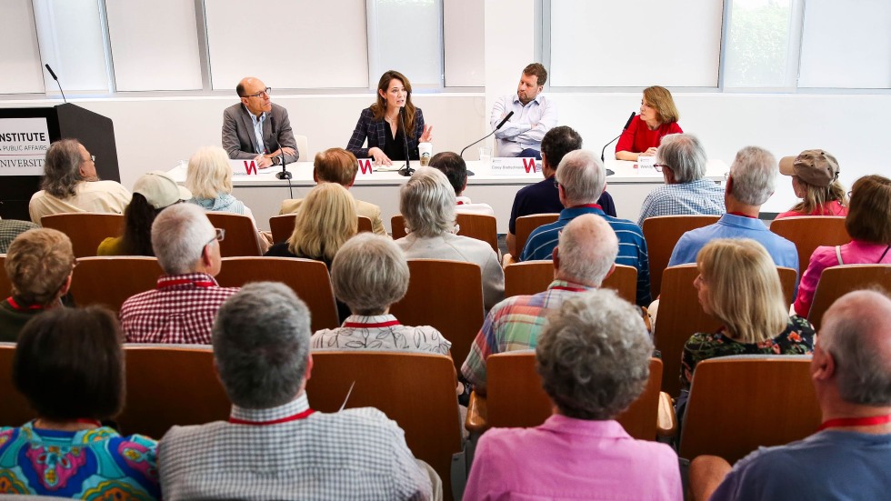 Four panelists speak before an audience
