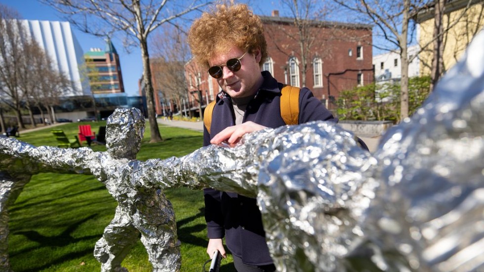 Student touches Circle Dance sculpture